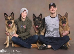 Man and Woman smiling with their three dogs