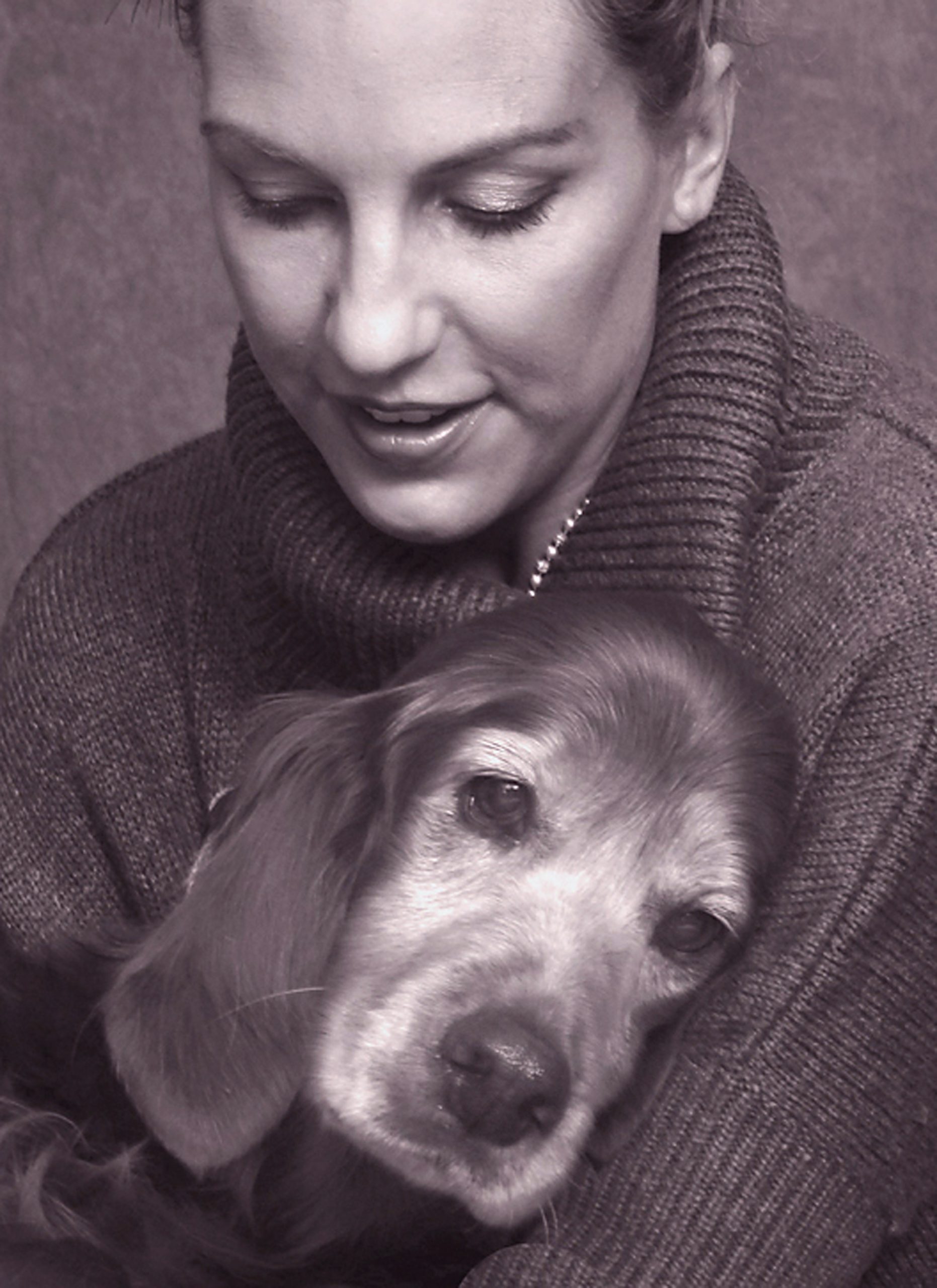 Woman holding her dying old dog in grayscale